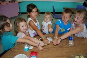 Young friends make button bracelets to raise money for cancer patients at Hugs & Kisses in the K-Mart plaza in Royal Palm Beach. Photo by Elien Boes