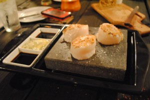 Scallops served on a 800-degree volcanic rock hot plate at your table.